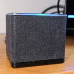 A close-up of the Fire TV Cube (2022) with its blue Alexa bar glowing